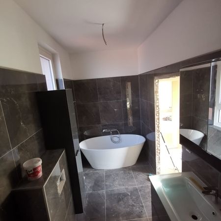 Modernes Badezimmer mit freistehender Badewanne und dunklen Fliesen