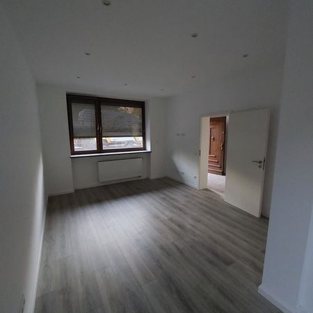 Renovierter Wohnbereich mit neu verlegtem Laminatboden und heller Wandgestaltung